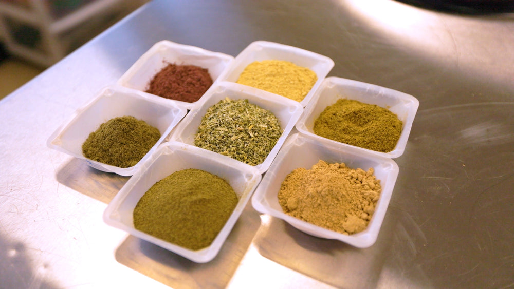 Assorted spices in small white containers on a metallic surface