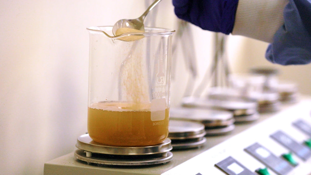 Person in a lab setting pouring a liquid into a container with a focus on precision.