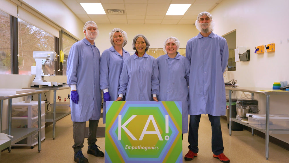 Group of people in a laboratory setting holding a sign with 'KA Empathogenics'.